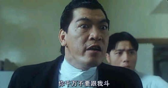 一位男子表情激動，對著前方說‘你千萬不要跟我斗’，身後站著另一位男子。